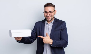 Genç yakışıklı adam neşeyle gülümsüyor, mutlu hissediyor ve bir tarafı işaret ediyor. beyaz kutu kavramı