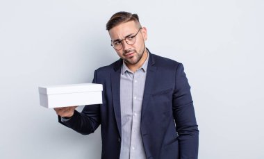 Genç ve yakışıklı bir adam üzgün, üzgün ya da kızgın hissediyor ve yan tarafa bakıyor. beyaz kutu kavramı