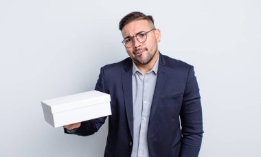 Kafası karışmış ve kafası karışmış genç yakışıklı bir adam. beyaz kutu kavramı