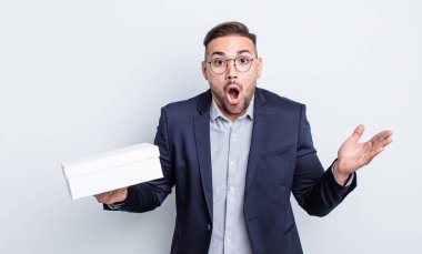 Genç, yakışıklı adam şaşırmış ve şok olmuş görünüyor. Çenesi düşmüş, elinde bir nesne var. beyaz kutu kavramı