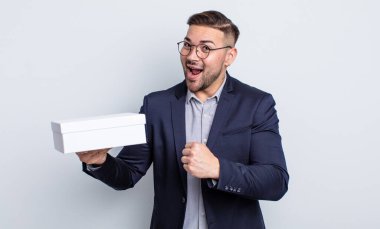 Genç yakışıklı adam kendini mutlu hissediyor ve bir meydan okumayla yüzleşiyor ya da kutluyor. beyaz kutu kavramı