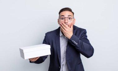 Genç ve yakışıklı bir adam elleri ile ağzını kapatıyor ve şok geçiriyor. beyaz kutu kavramı