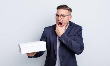 Ağzı ve gözleri açık ve eli çenesinde genç yakışıklı bir adam. beyaz kutu kavramı