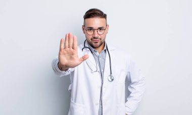 Genç ve yakışıklı adam ciddi görünüyor. Avuç içi gösteriyor. Durdurma hareketi yapıyor. hekimlik kavramı