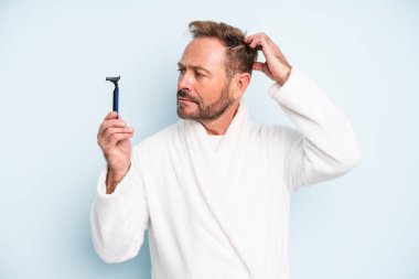 Orta yaşlı bir adam mutlu bir şekilde gülümsüyor ve hayal kuruyor ya da şüphe ediyor. traş konsepti