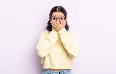 Güzel genç bir kadın elleri ile ağzını kapatıyor, şok olmuş, şaşırmış bir ifadeyle, sır saklıyor ya da 
