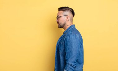 Profil görünümündeki genç yakışıklı adam ilerideki boşluğu kopyalamaya çalışıyor, düşünüyor, hayal ediyor ya da hayal kuruyor.