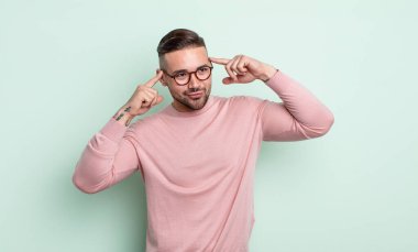 Genç ve yakışıklı bir adam kafası karışmış ya da şüphe içinde, bir fikre odaklanmış, çok düşünüyor, kenarda boşluğu kopyalamaya çalışıyor.