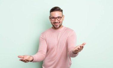 Genç yakışıklı adam neşeyle gülümsüyor sıcak, dostça, sevgi dolu bir kucak veriyor, mutlu ve sevimli hissediyor.