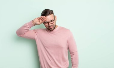 Genç yakışıklı adam stresli, yorgun ve hayal kırıklığına uğramış, alnından ter damlayan, umutsuz ve bitkin hisseden.