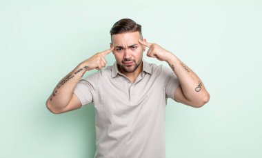 Ciddi ve konsantre görünümlü, beyin fırtınası yapan ve zorlu bir sorunu düşünen genç yakışıklı bir adam.