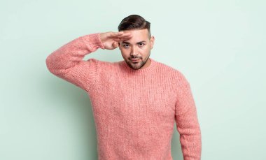 Genç ve yakışıklı bir adam saygı göstererek, onur ve vatanseverlik adına askeri bir selamla kamerayı selamlıyor.