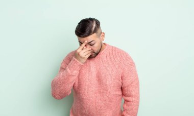 Genç yakışıklı, stresli, mutsuz ve hayal kırıklığına uğramış, alınlı ve şiddetli baş ağrısı çeken bir adam.