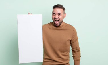 Genç, yakışıklı, neşeli ve asi tavırlı, şaka yapan ve dilini dışarı çıkaran bir adam. boş tuval kavramı