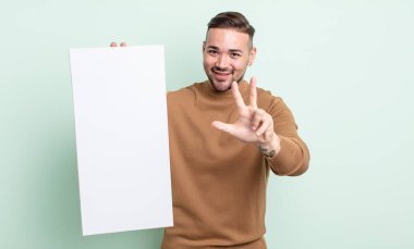 Genç yakışıklı adam gülümsüyor ve arkadaş canlısı görünüyor, üç numarayı gösteriyor. boş tuval kavramı