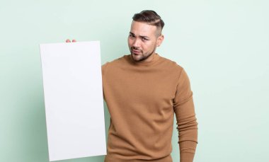 Genç ve yakışıklı bir adam üzgün, üzgün ya da kızgın hissediyor ve yan tarafa bakıyor. boş tuval kavramı