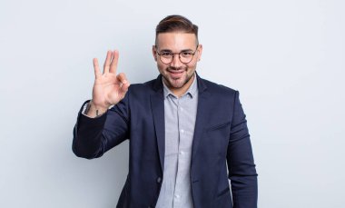 Genç yakışıklı adam kendini mutlu hissediyor, iyi bir jestle onaylıyor. İş adamı konsepti