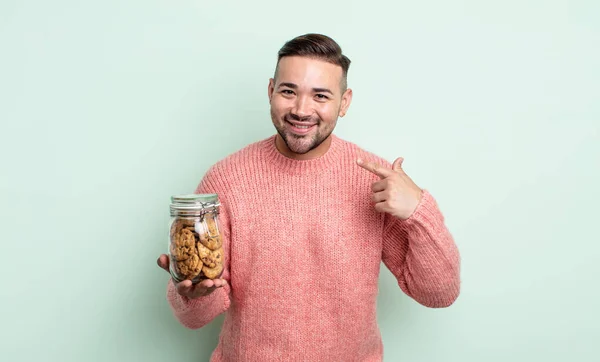 若いハンサムな男は自信を持って笑顔を指す クッキーボトルのコンセプト — ストック写真