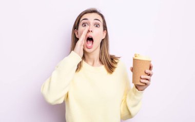 Genç, güzel bir kadın kendini mutlu hissediyor. Elleri ağzının kenarında bağırıyor. kahve konseptini kaldır.