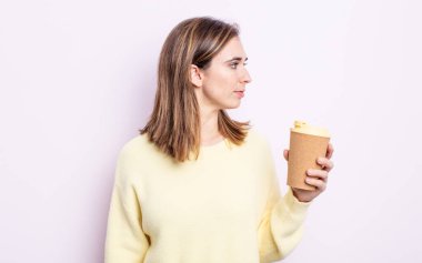 Profil görünümlü genç, güzel bir kadın hayal kuruyor ya da hayal kuruyor. kahve konseptini kaldır.