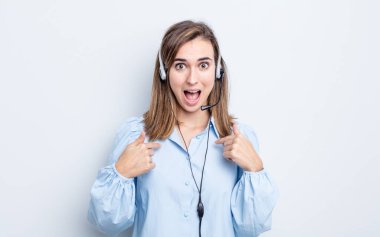 Genç ve güzel bir kadın kendini mutlu hissediyor ve heyecanlı bir şekilde kendini işaret ediyor. tele pazarlamacı kavramı