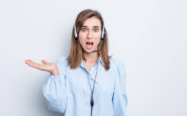 Genç ve güzel bir kadın şaşırmış ve şok olmuş görünüyor. Çenesi düşmüş ve elinde bir nesne tutuyor. tele pazarlamacı kavramı