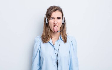 Genç ve güzel bir kadın iğreniyor, sinirleniyor ve dilini çıkarıyor. tele pazarlamacı kavramı