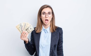 Genç ve güzel bir kadın çok şaşırmış ya da şaşkın görünüyor. Dolar banknotları konsepti