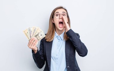 Genç, güzel bir kadın kendini mutlu hissediyor. Elleri ağzının kenarında bağırıyor. Dolar banknotları konsepti