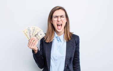 Genç ve güzel bir kadın agresif bir şekilde bağırıyor, çok kızgın görünüyor. Dolar banknotları konsepti