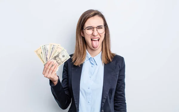 陽気で反抗的な態度の若い可愛い女が冗談を言って舌を出してる ドル紙幣の概念 — ストック写真