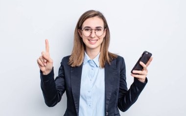 Genç, güzel bir bayan gülümsüyor ve arkadaş canlısı görünüyor. Bir numarayı gösteriyor. iş kavramı