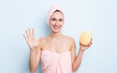 Genç, güzel bir bayan gülümsüyor ve arkadaş canlısı görünüyor, beş numarayı gösteriyor. duş ve sünger konsepti