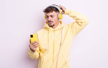 Genç yakışıklı adam mutlu bir şekilde gülümsüyor ve hayal kuruyor ya da şüphe ediyor. müzik konsepti