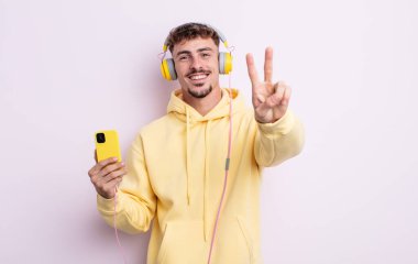 Genç yakışıklı adam gülümsüyor ve mutlu görünüyor, zafer ya da barış işareti yapıyor. müzik konsepti
