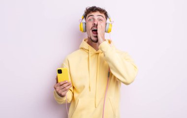 Genç yakışıklı adam mutlu hissediyor, elleri ağzının kenarında bağırıyor. müzik konsepti