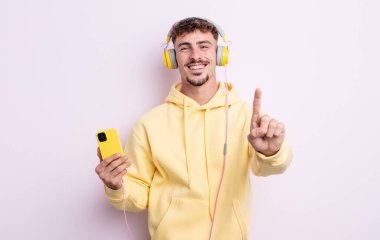 Genç yakışıklı adam gülümsüyor ve arkadaş canlısı görünüyor, bir numarayı gösteriyor. müzik konsepti