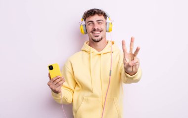 Genç yakışıklı adam gülümsüyor ve arkadaş canlısı görünüyor, üç numarayı gösteriyor. müzik konsepti
