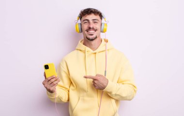 Genç yakışıklı adam neşeyle gülümsüyor, mutlu hissediyor ve bir tarafı işaret ediyor. müzik konsepti