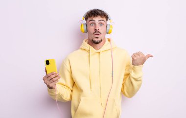 İnanamadığı için şaşırmış genç ve yakışıklı bir adam. müzik konsepti