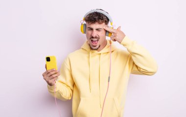 Genç yakışıklı adam mutsuz ve stresli görünüyor, intihar jesti silah işareti yapıyor. müzik konsepti
