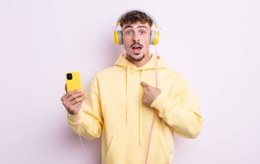Şok olmuş ve ağzı açık, kendini işaret eden genç ve yakışıklı bir adam. müzik konsepti