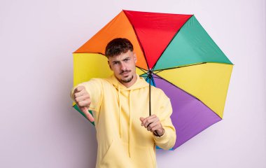 Genç ve yakışıklı bir adam kendini kötü hissediyor, baş parmağını kaldırıyor. şemsiye kavramı