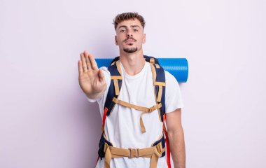 Genç ve yakışıklı adam ciddi görünüyor. Avuç içi gösteriyor. Durdurma hareketi yapıyor. Yürüyüş konsepti