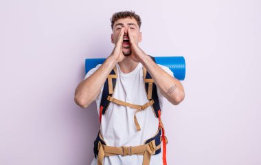 Genç yakışıklı adam mutlu hissediyor, elleri ağzının kenarında bağırıyor. Yürüyüş konsepti