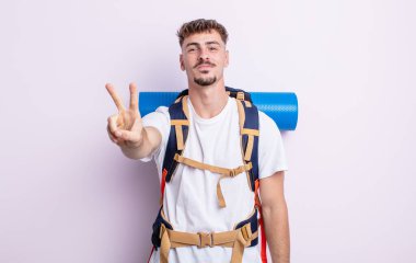 Genç yakışıklı adam gülümsüyor ve mutlu görünüyor, zafer ya da barış işareti yapıyor. Yürüyüş konsepti