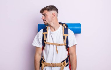 Profilde genç yakışıklı bir adam hayal kuruyor, hayal kuruyor ya da hayal kuruyor. Yürüyüş konsepti