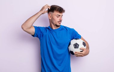 Genç yakışıklı adam mutlu bir şekilde gülümsüyor ve hayal kuruyor ya da şüphe ediyor. futbol kavramı
