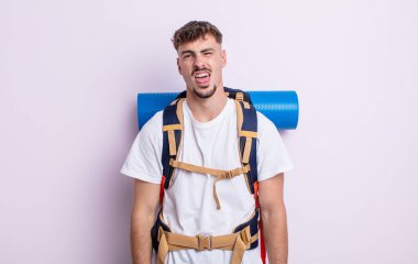 Genç ve yakışıklı bir adam tiksinmiş ve sinirlenmiş hissediyor ve dilini dışarı çıkarıyor. Yürüyüş konsepti