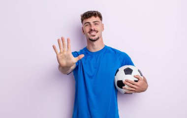 Genç yakışıklı adam gülümsüyor ve arkadaş canlısı görünüyor, beş numarayı gösteriyor. futbol kavramı